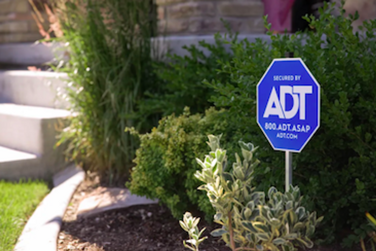 a photo of ADT sign in a garden