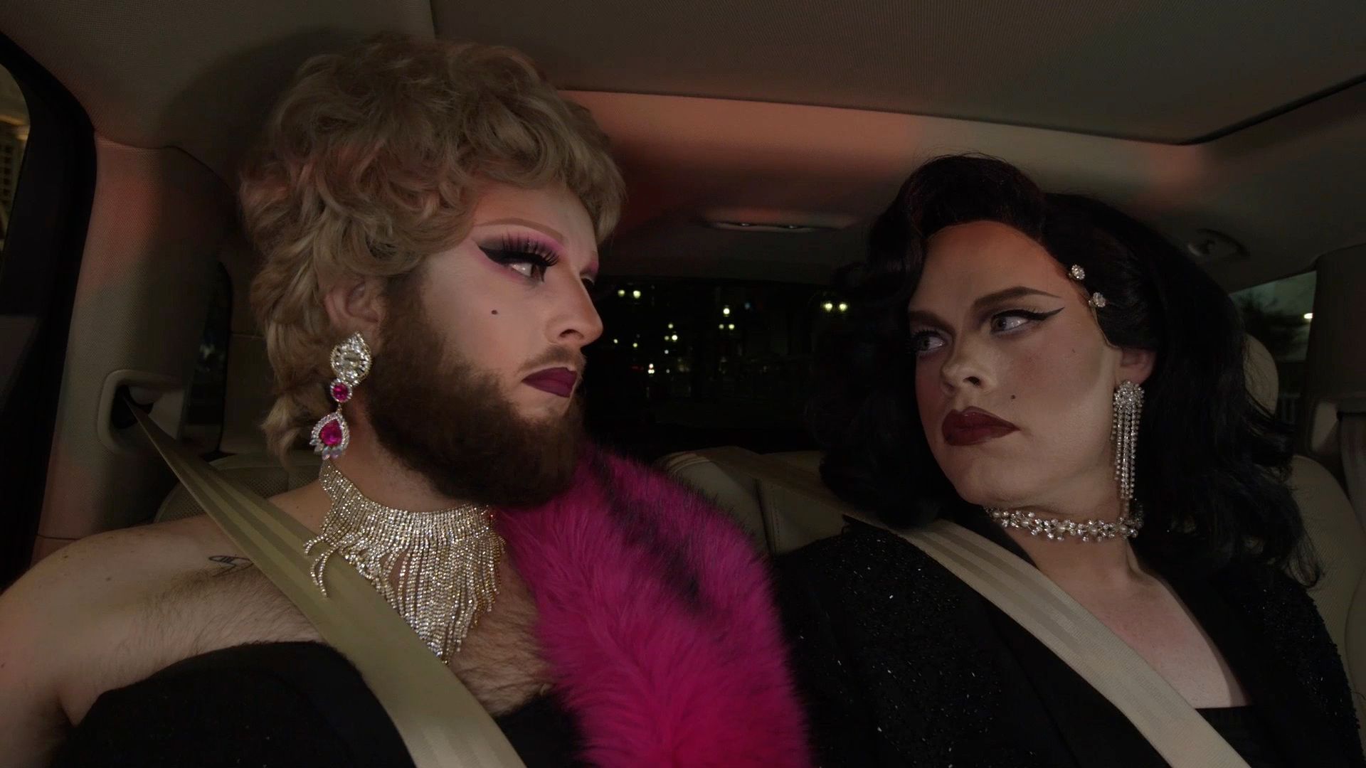 Two drag queens give each other a shocked look