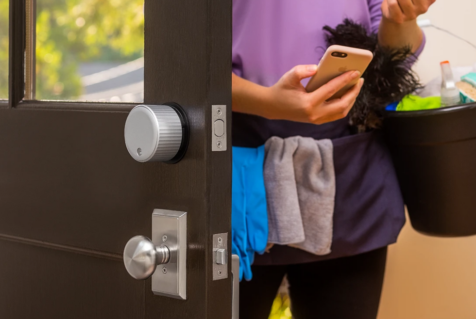 a photo of a woman entering a home with August Smart Lock on the door.