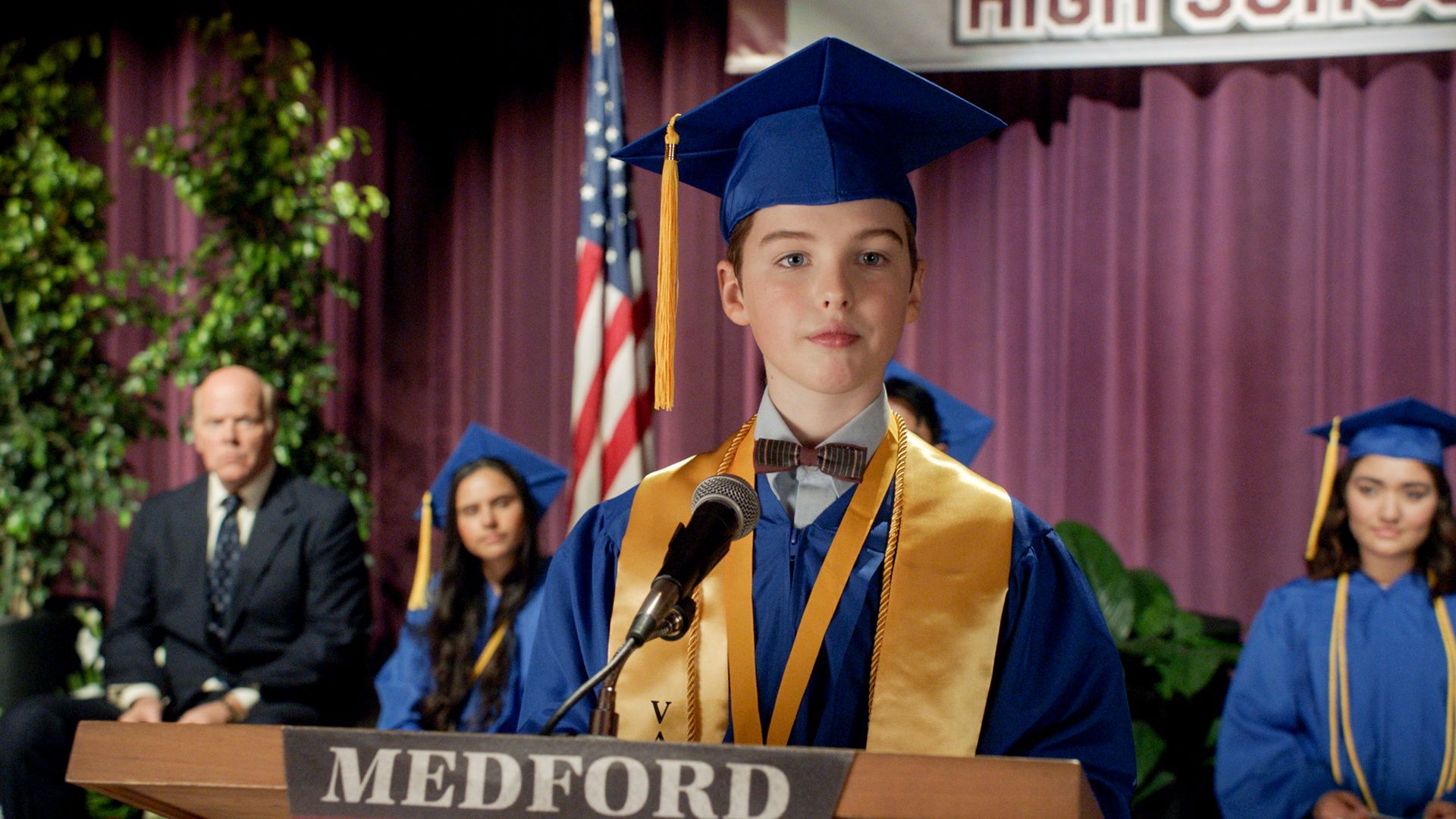 Sheldon in a blue cap and gown at his graduation ceremony