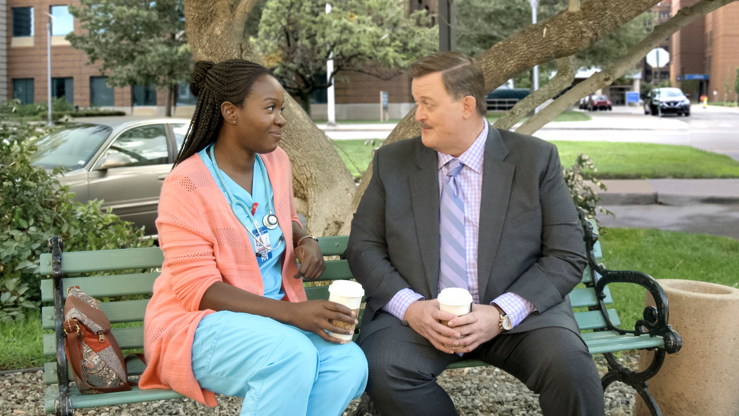 Abishola and Bob on a park bench for their coffee date