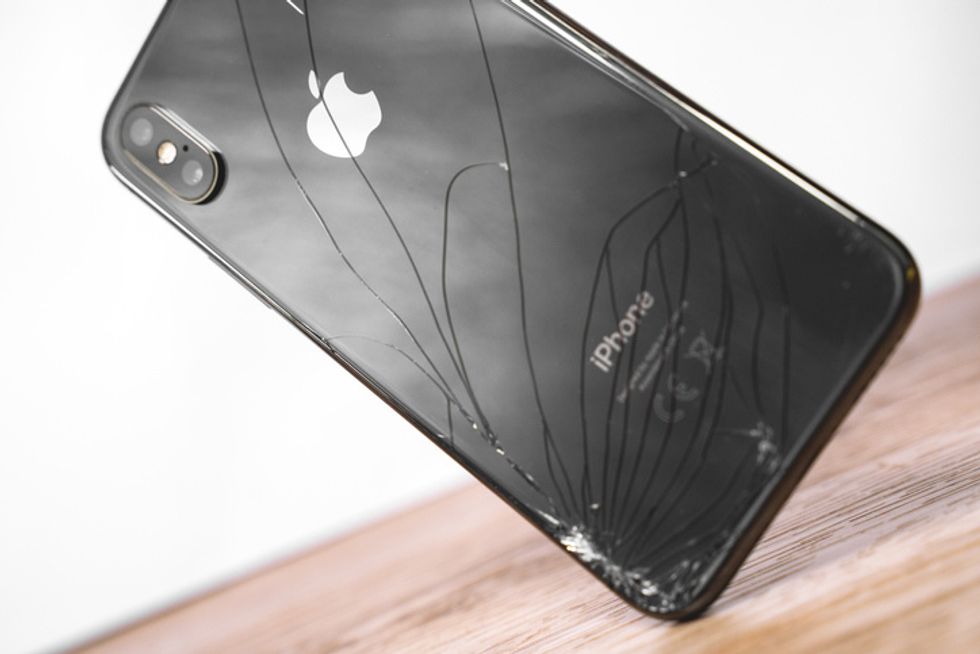 iPhone Ten X with broken display drop to the floor. Modern smartphone with damaged glass screen. Device needs repair
