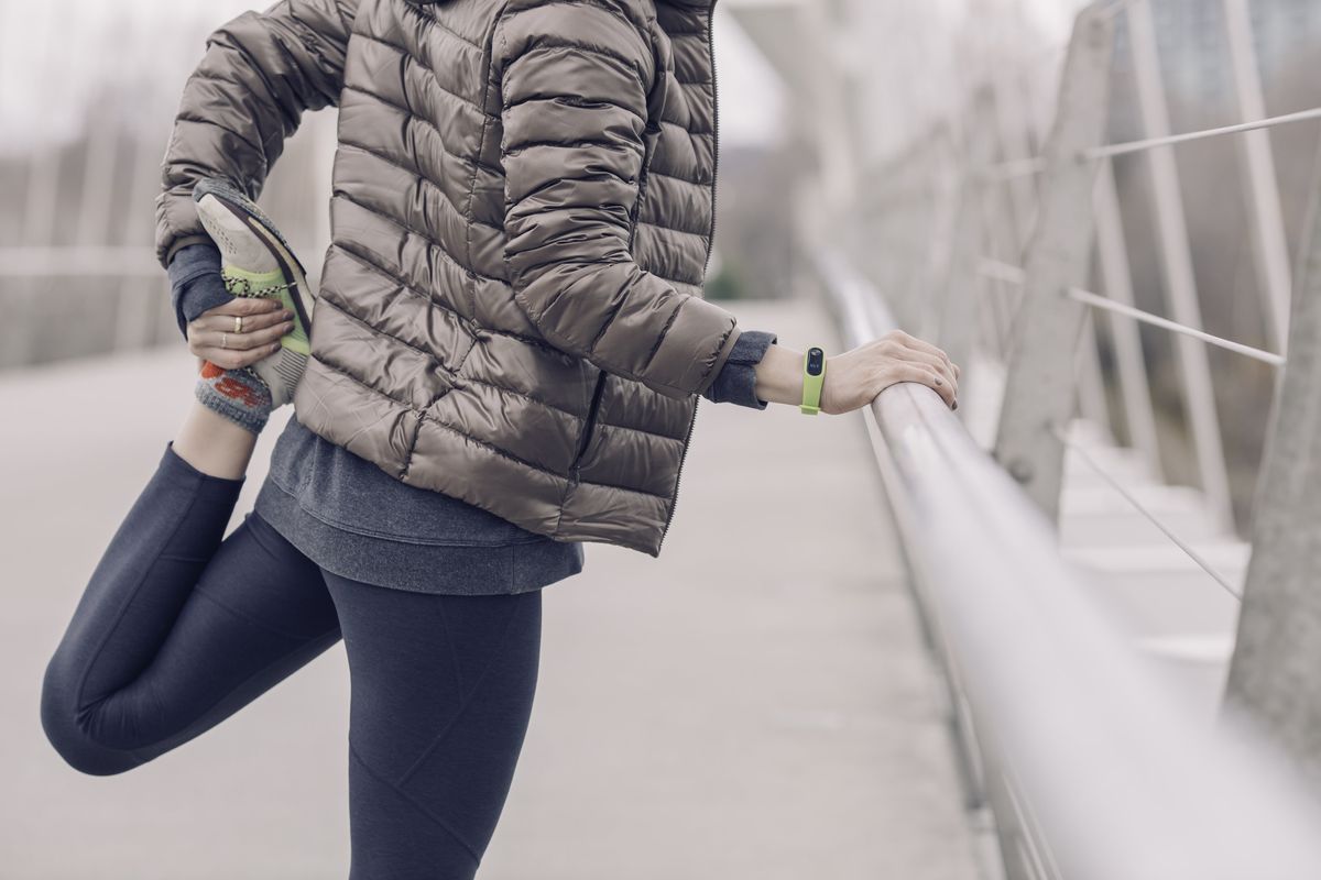 woman stretching before a run in winter running gear