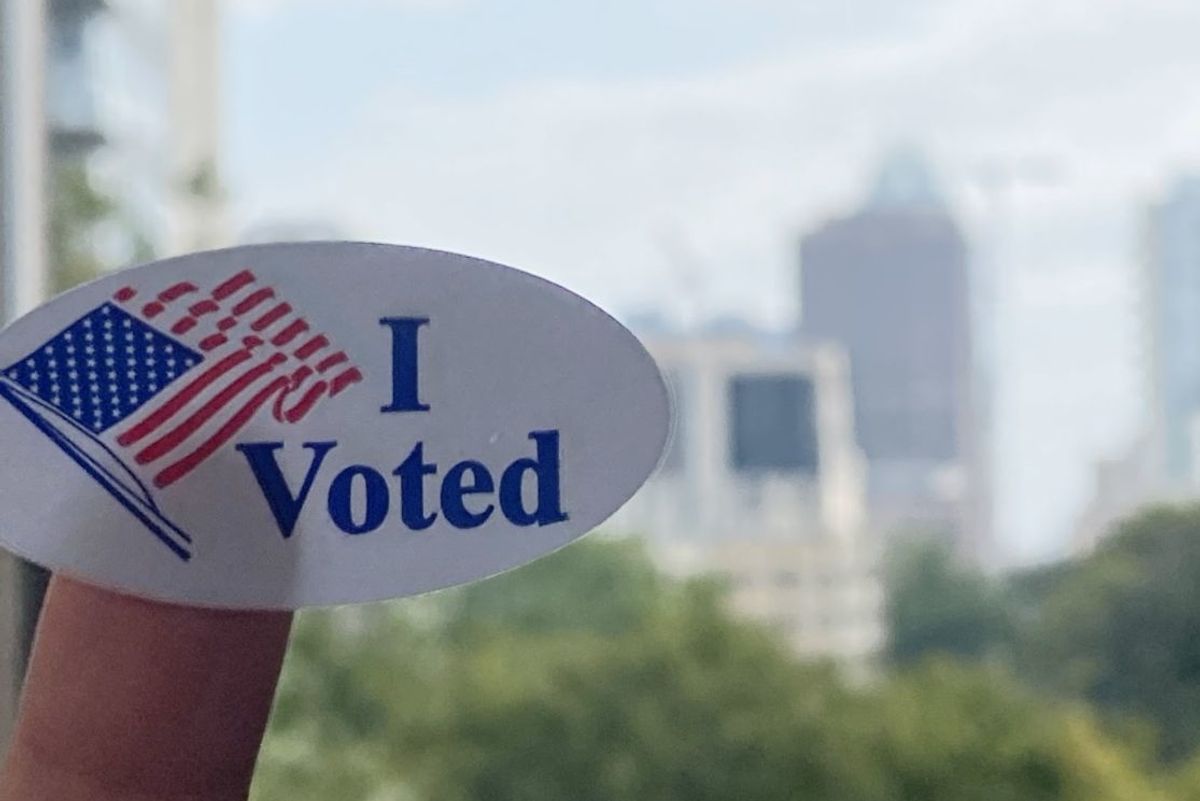 An "I voted" sticker stuck to a finger against the Austin