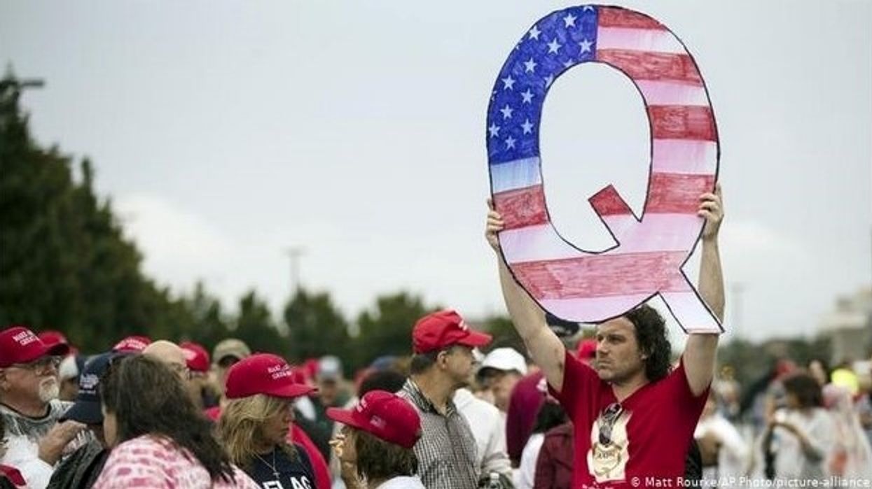 Man holding the Qanon symbol 