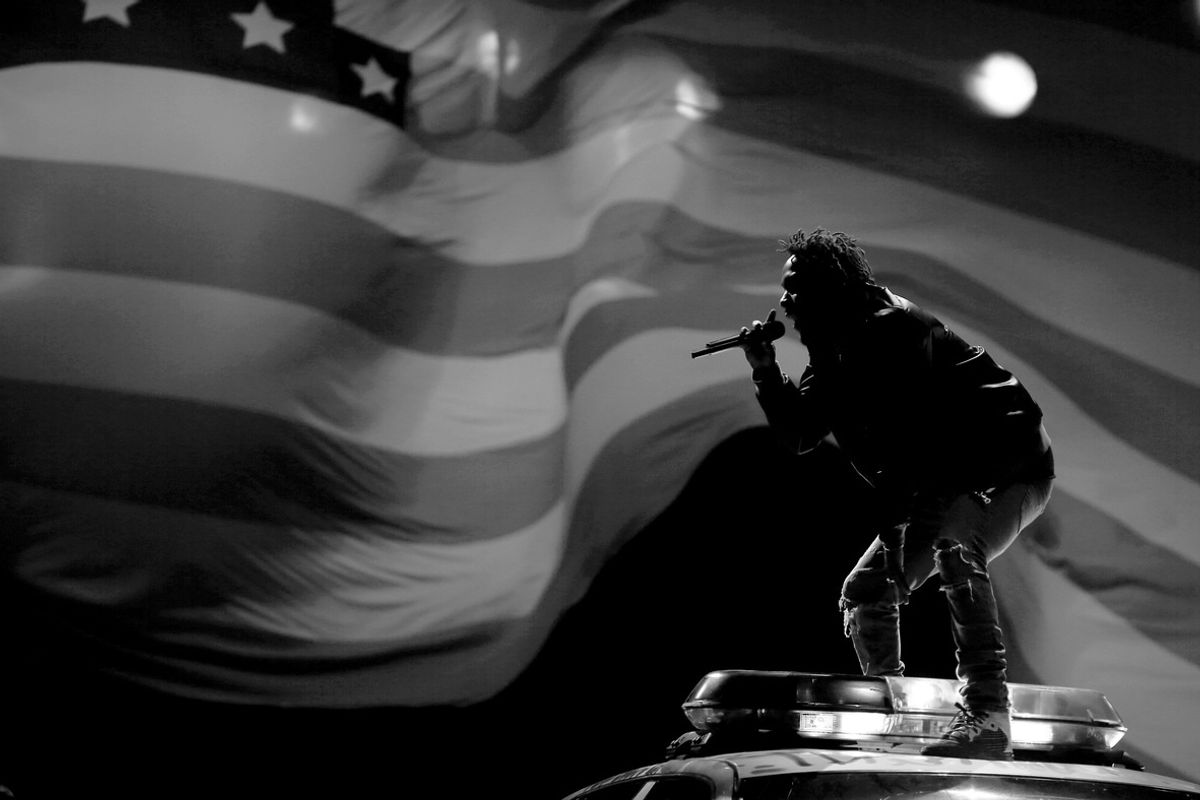 kendrick lamar on top of a police car in front of an American flag