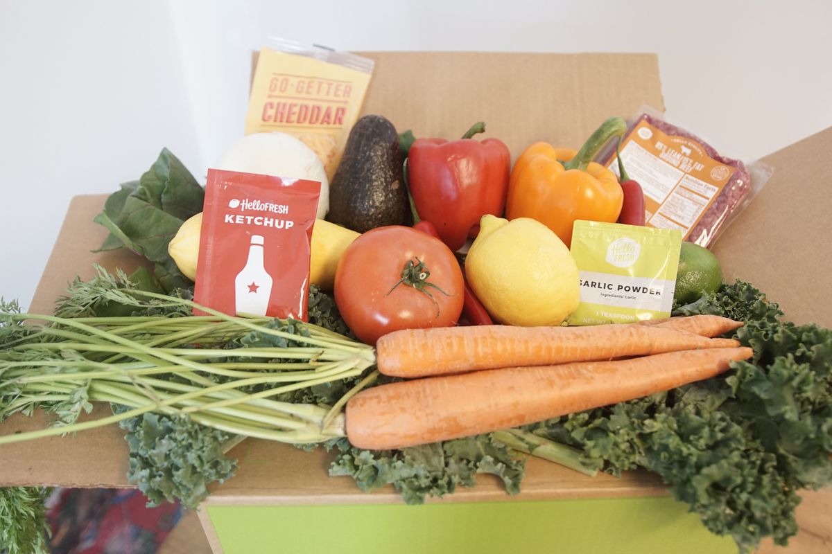 carrots, peppers, lemon, avocado, meat, and cheddar emerging from a HelloFresh box
