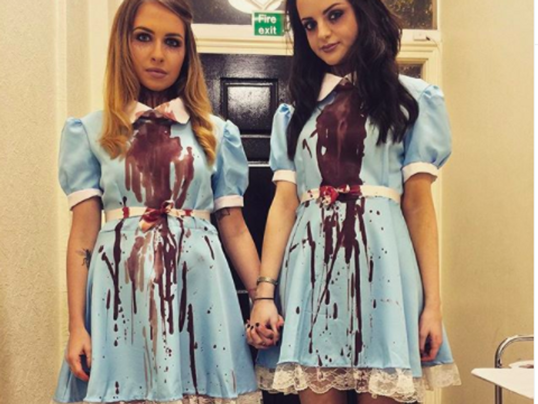 two people wearing blue dresses covered in red stains