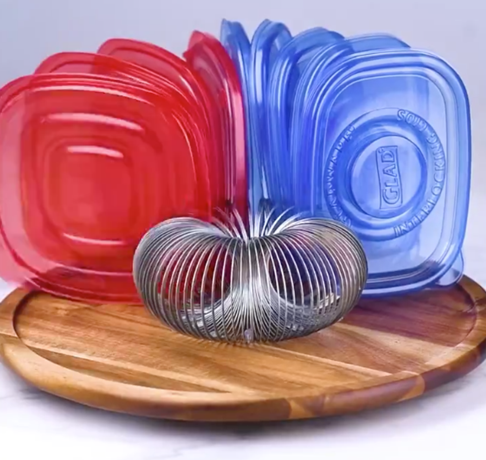 A slinky sits on a lazy susan. Between the coils, tupperware lids are held.