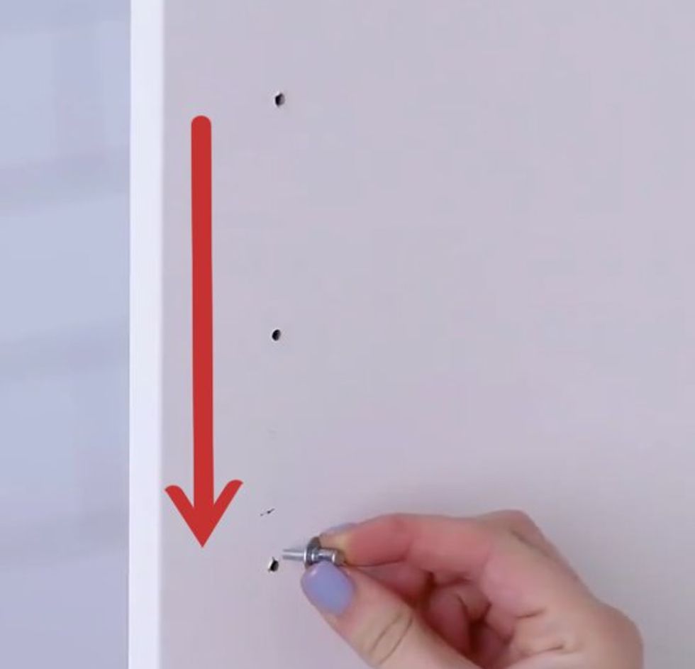 A hand pushes a pin into the door of a cupboard