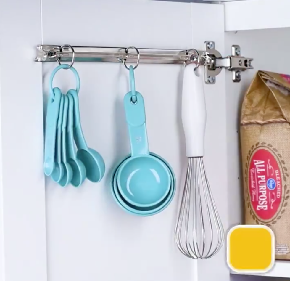 A whisk and measuring spoons hang from the metal rings