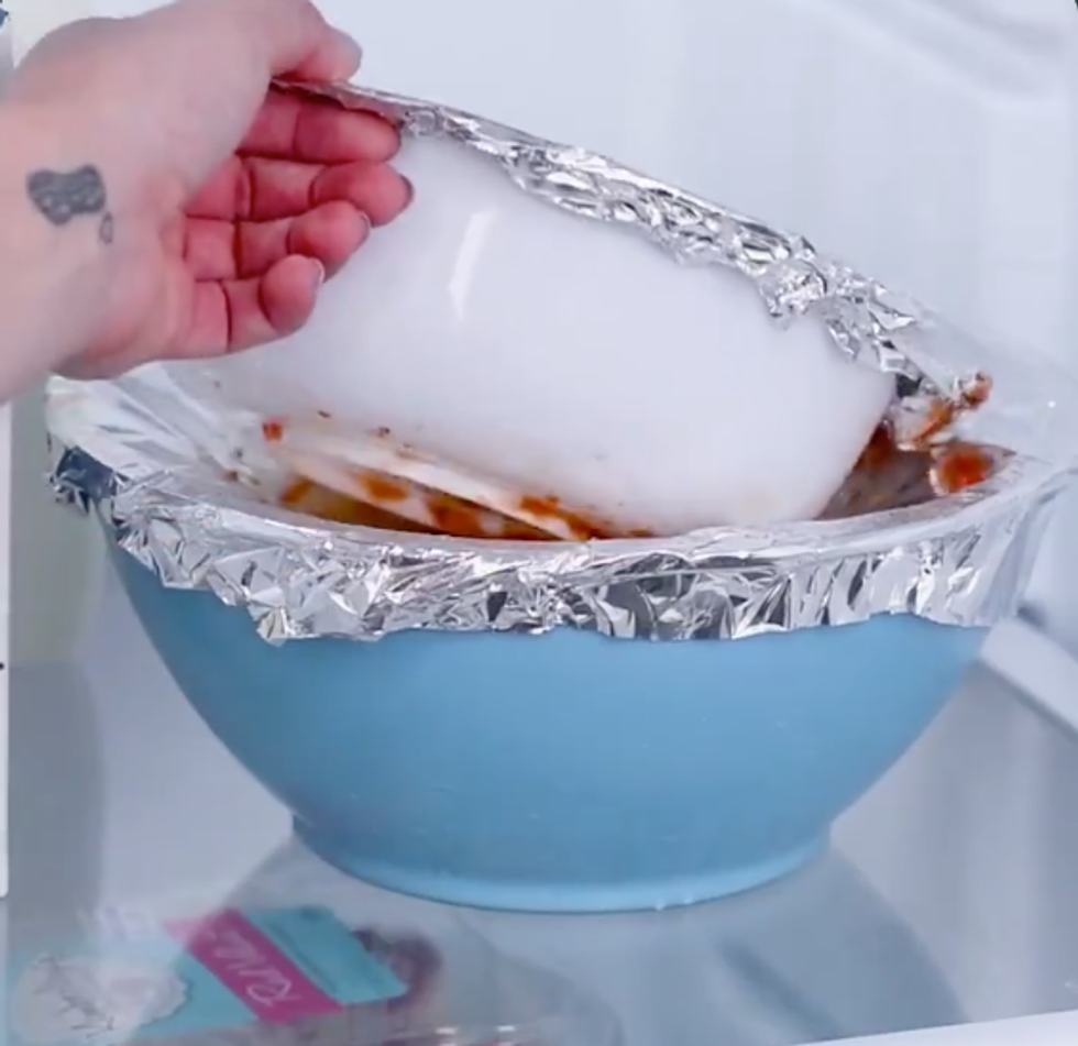 Someone places a plastic bowl covered in tinfoil on top of another bowl covered in tinfoil. It's very messy.