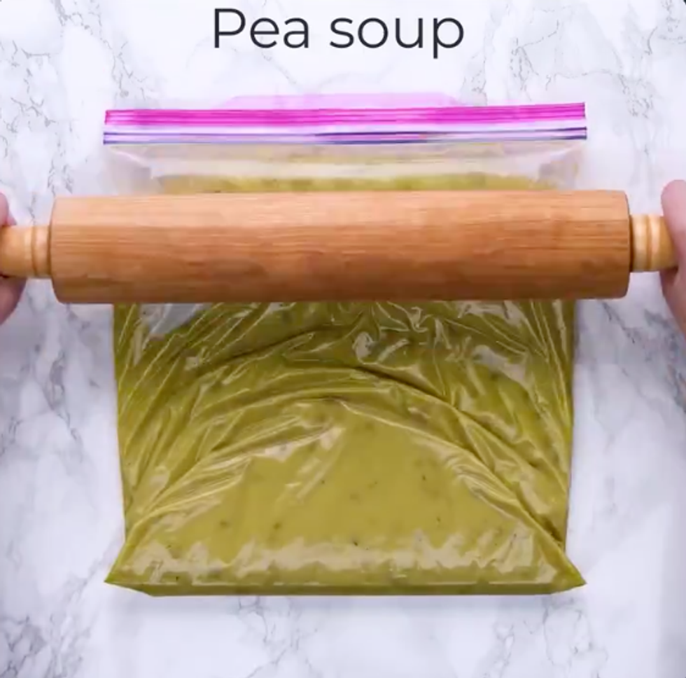 Someone uses a rolling pin on a bag of pea soup