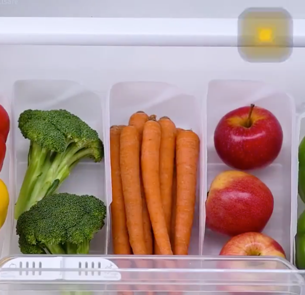 A drawer with those cut milk containers laying flat inside. Each one holds a type of vegetable