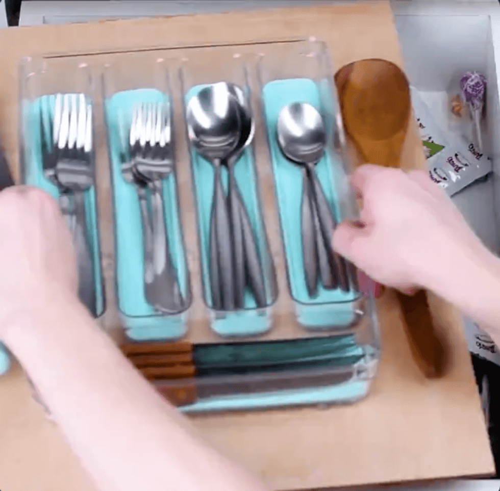 Drawer organizer full of silverware on top of plywood
