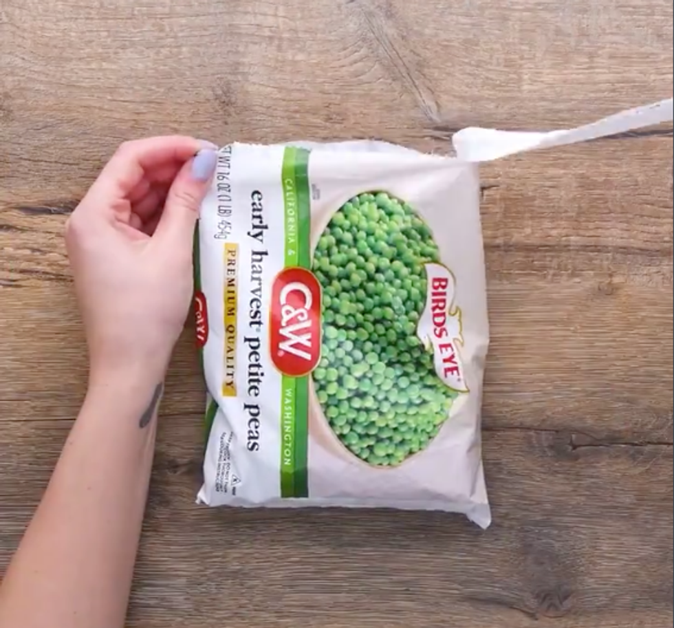 Hands opening a bag of frozen peas