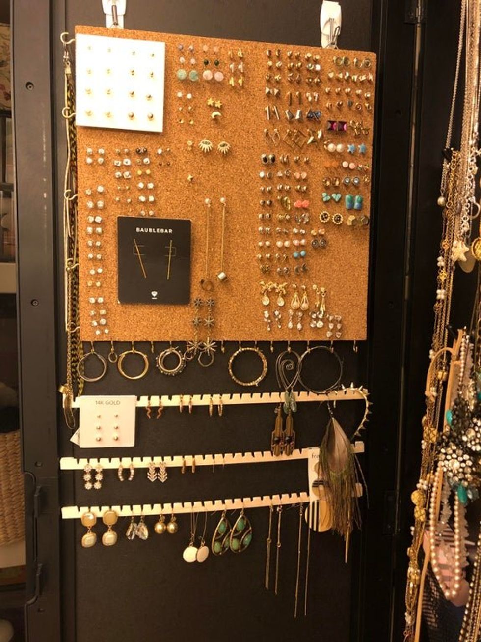 Corkboard is hung from the wall. Earrings are pushed into it to make a lovely display