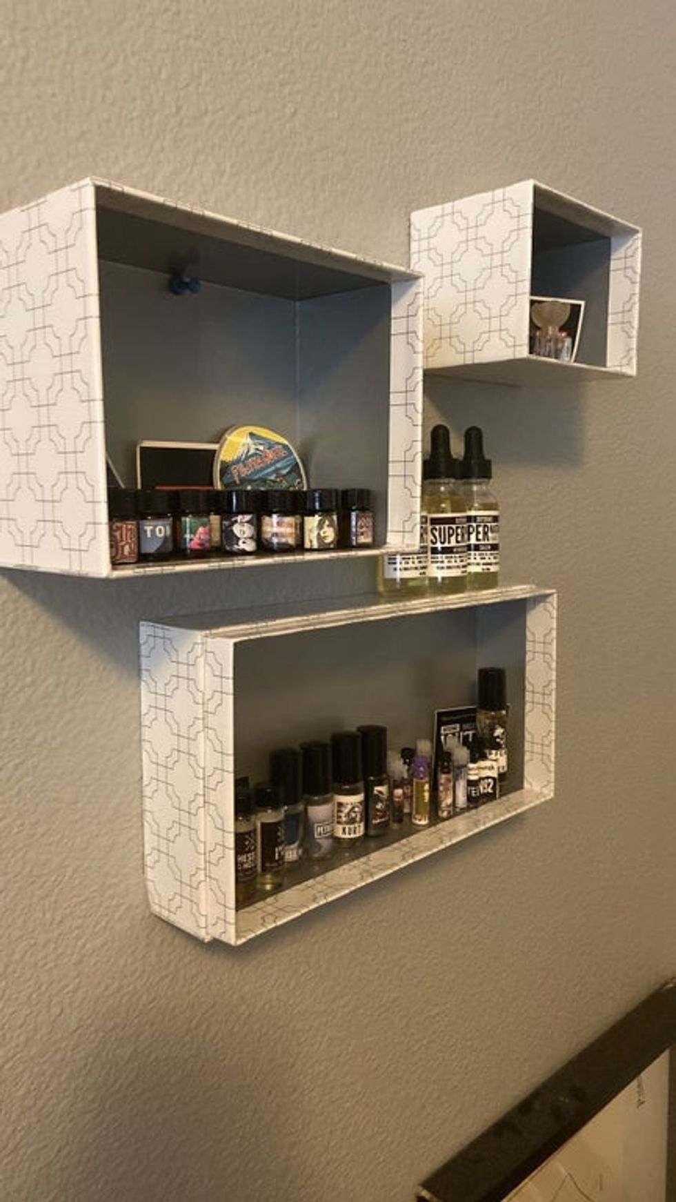 Shoeboxes have been push pinned to the wall with the bottom of the box flat against the wall. Items are placed inside.