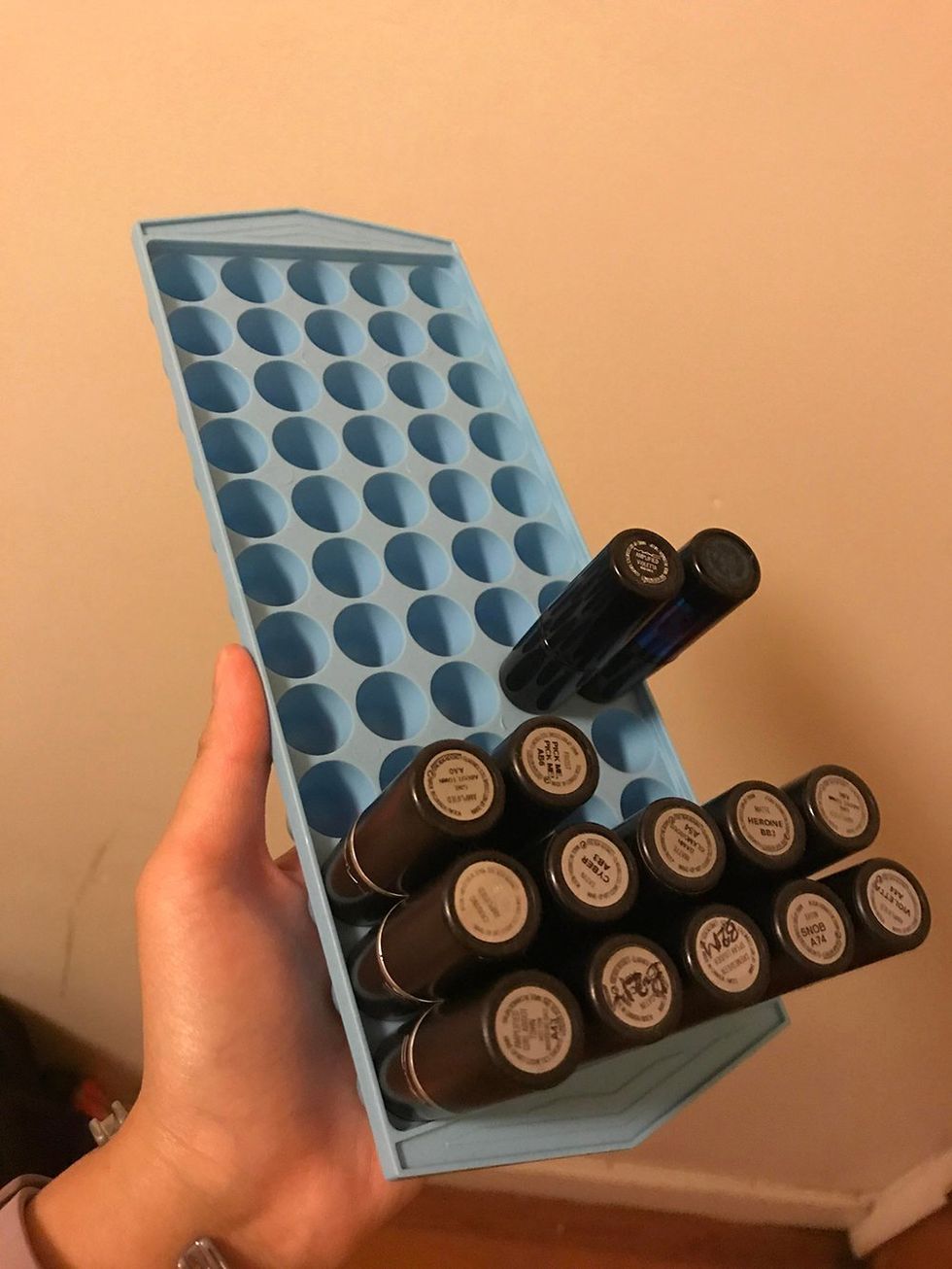 An ice cube tray has lipstick tubes stuck into each hole.