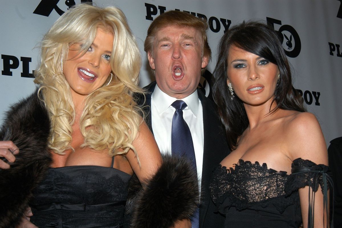 Donald Trump making a lewd face with two women on his arm. The playboy logo is in the background.