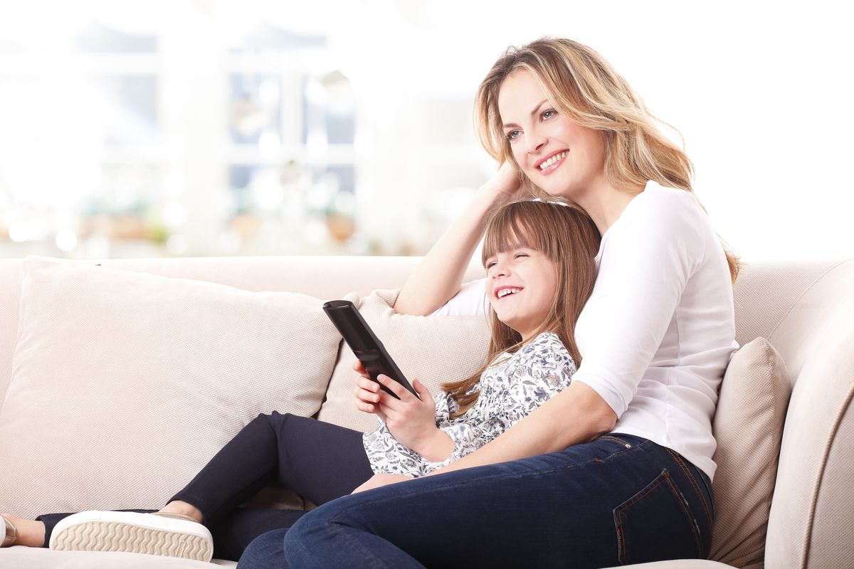 woman and her daughter sitting on a couch smiling