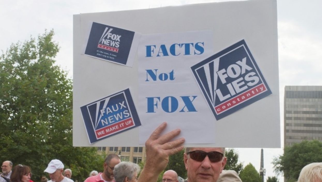 Man holding 'Facts Not Fox' sign