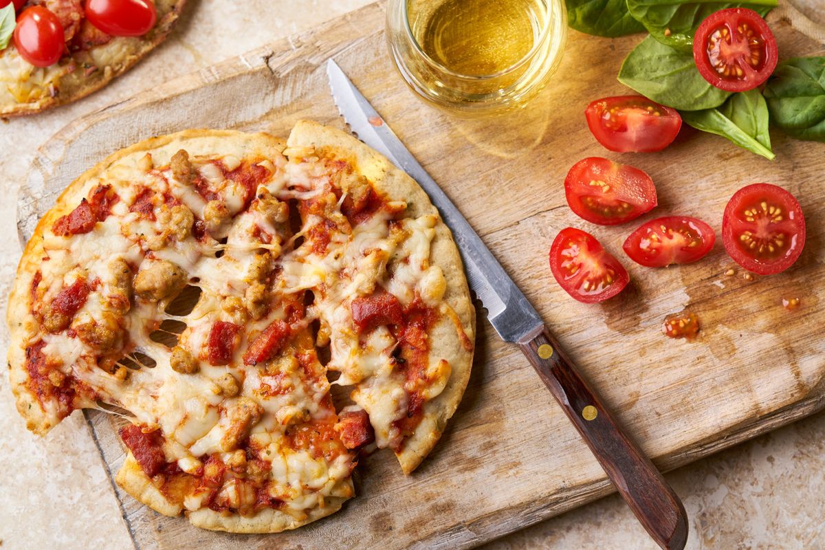 Pizza on a cutting board with tomatoes