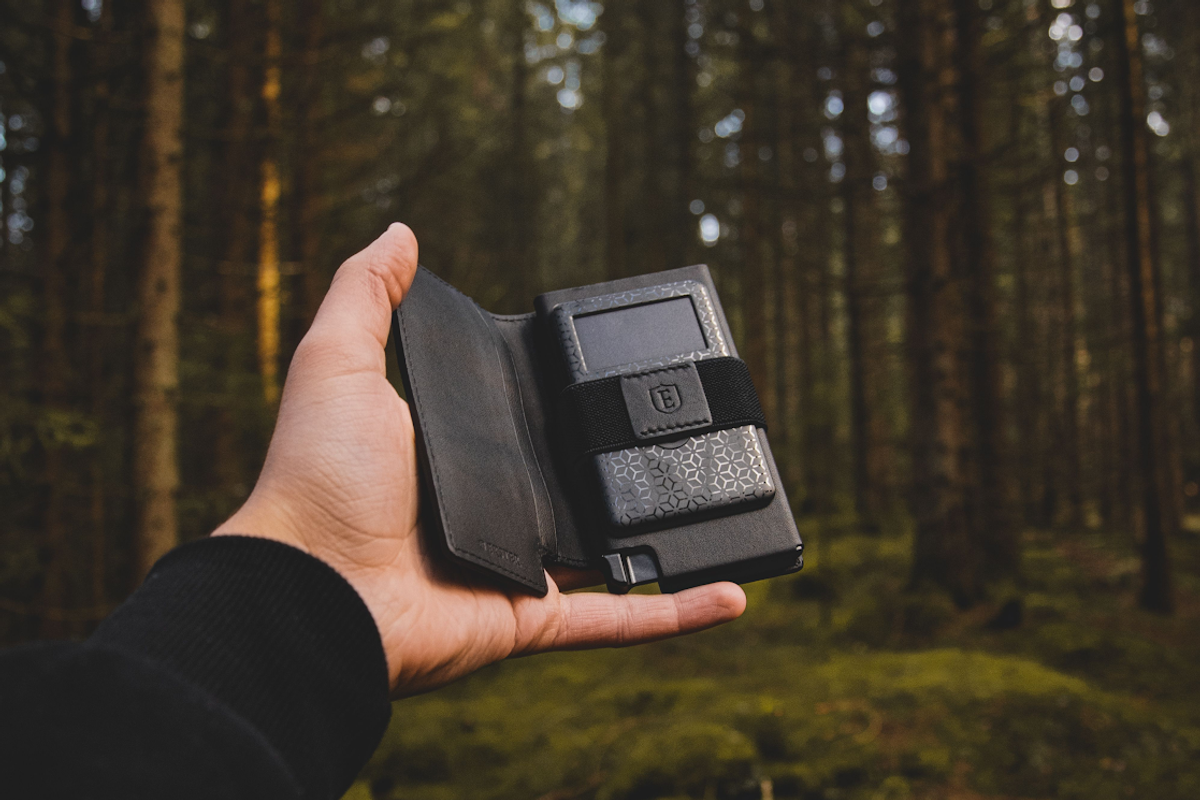hand holding Ekster wallet with tracker in the woods