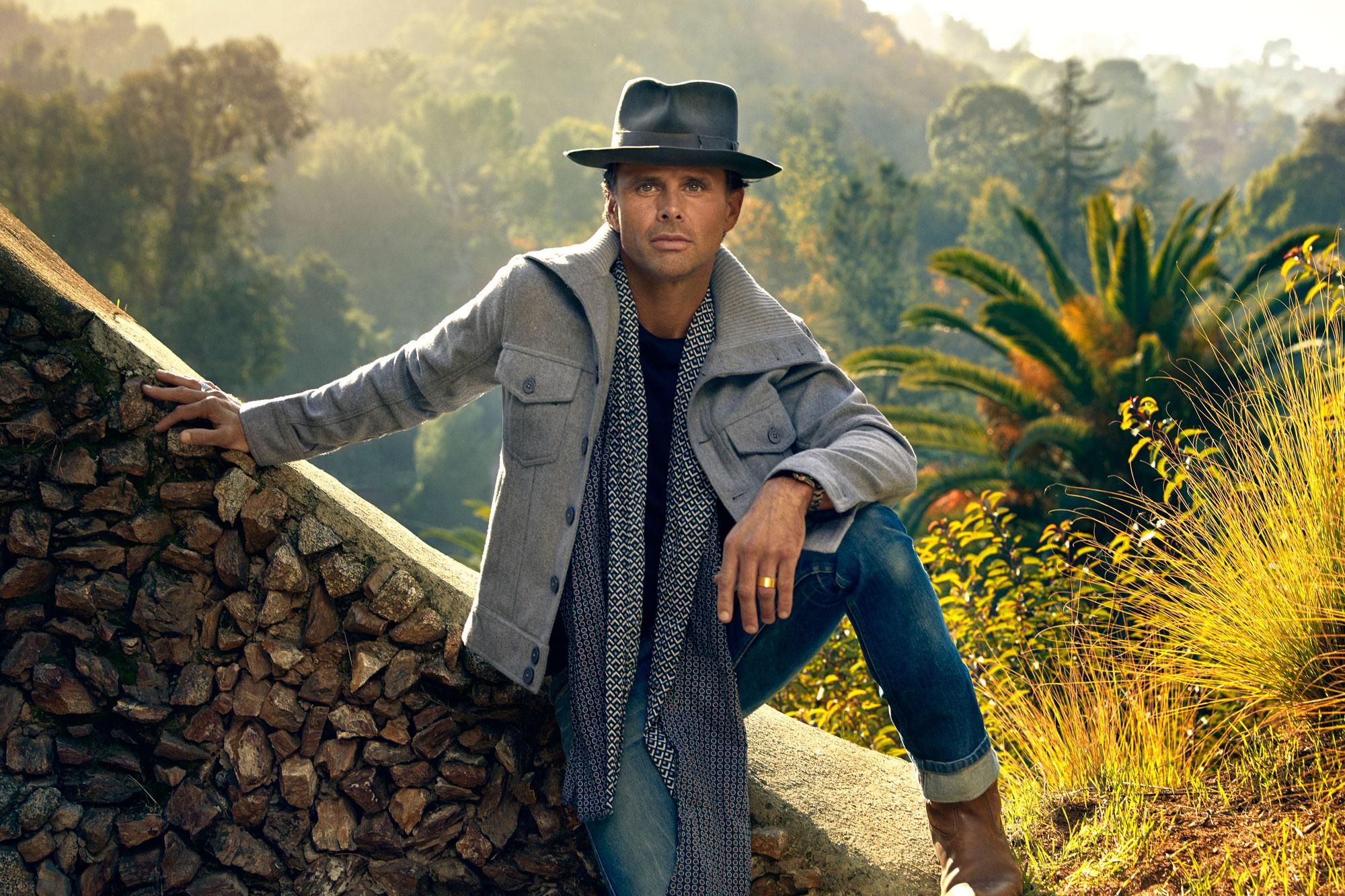 Walton Goggins sitting on a stone wall staring into the camera.