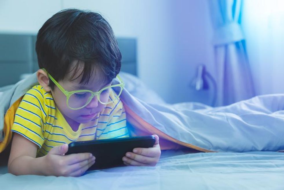 A child in a bed with a tablet
