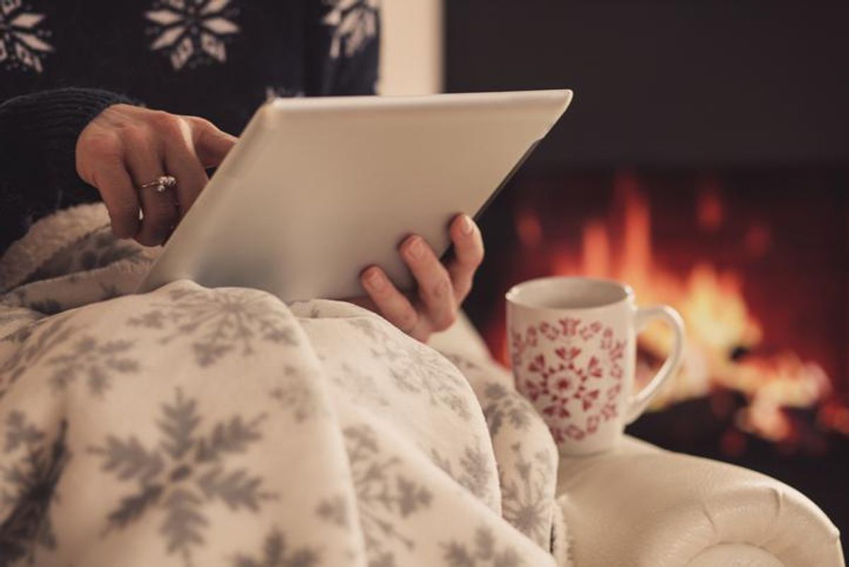 Someone holding a tablet, under a winter blanket