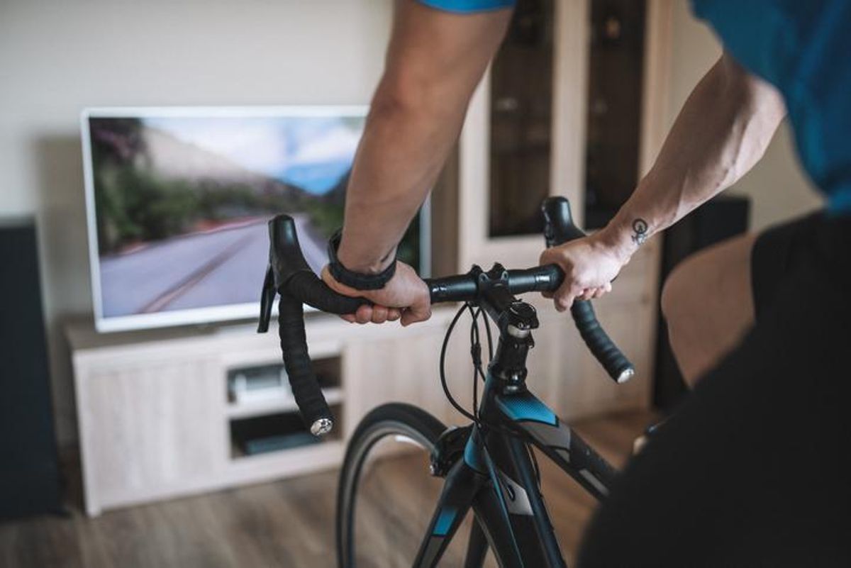 A man riding a stationary bike inside while doing a cycling exercise routine