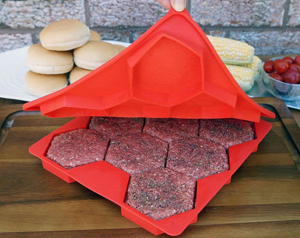 A burger press presses down raw burger patties.