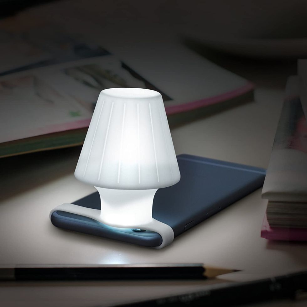 A small travel lamp is attached to an iphone.