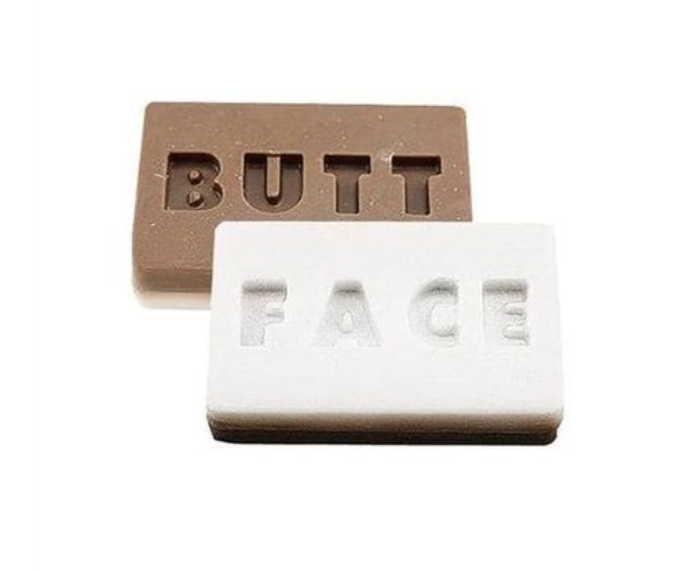 Two bars of soap one white with face printed on it and the other brown with butt printed on it.