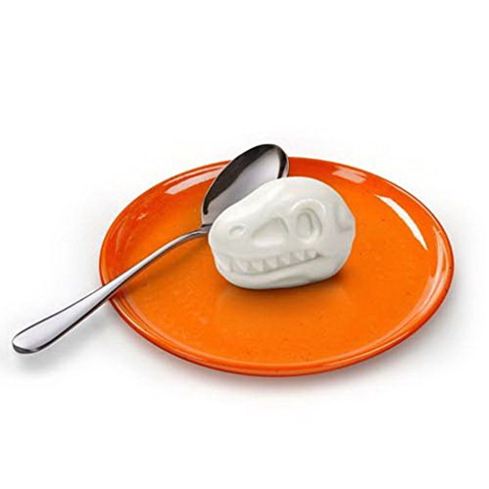 A hard boiled egg in the shape of a dinosaur head on an orange plate.
