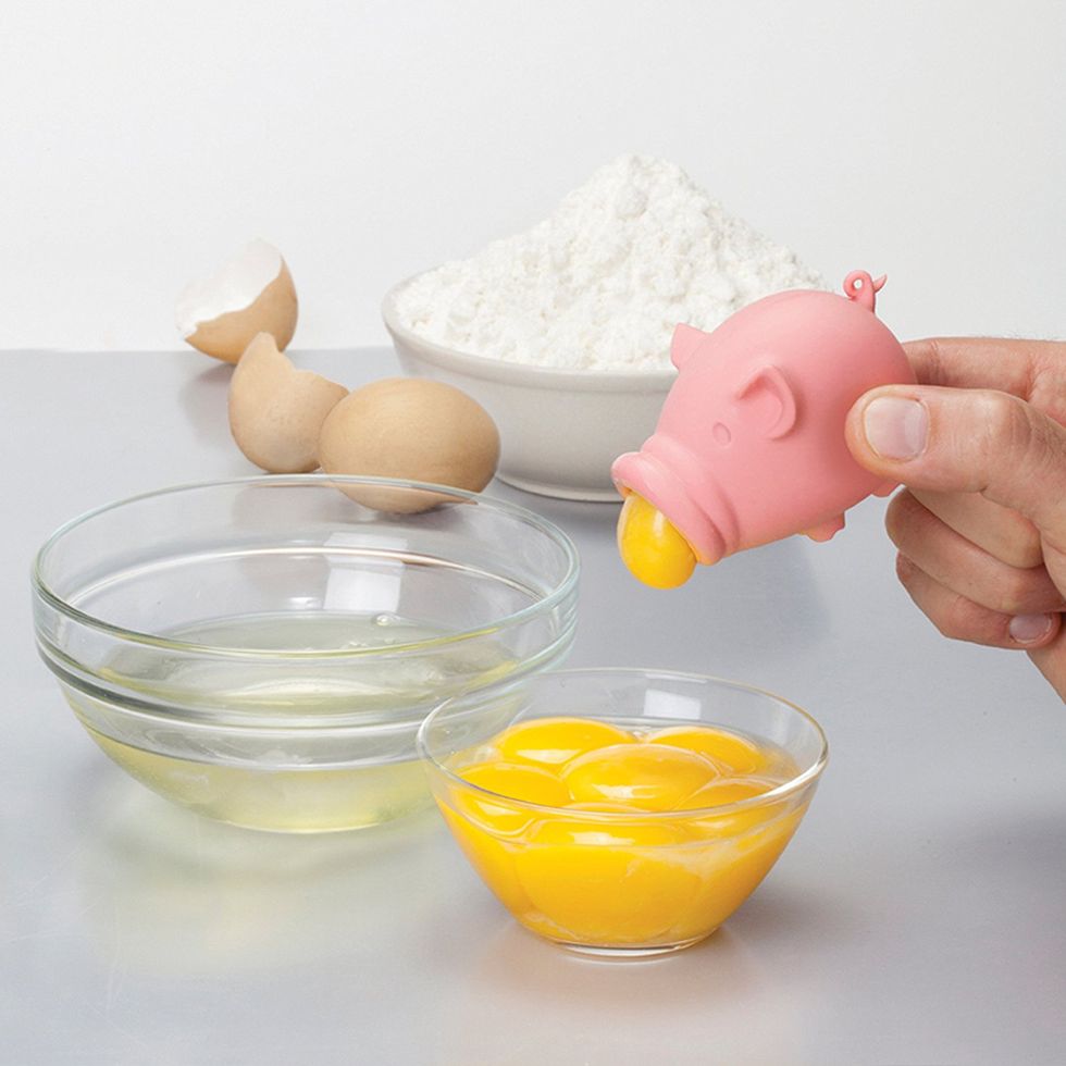An egg separator in the shape of a pig separating egg yolks into a bowl.