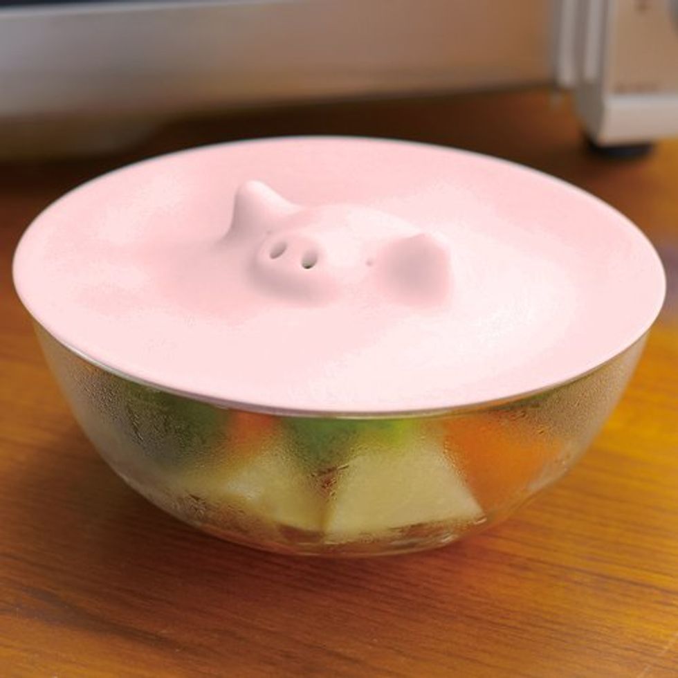 A steamer lid that's top is in the shape of a pink pig head.