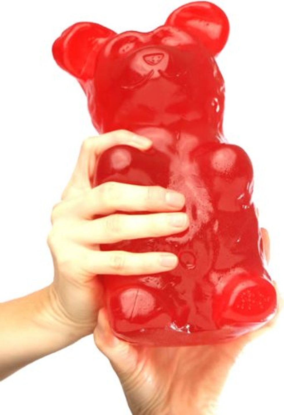 A giant gummy bear a person requires two hands to hold up.