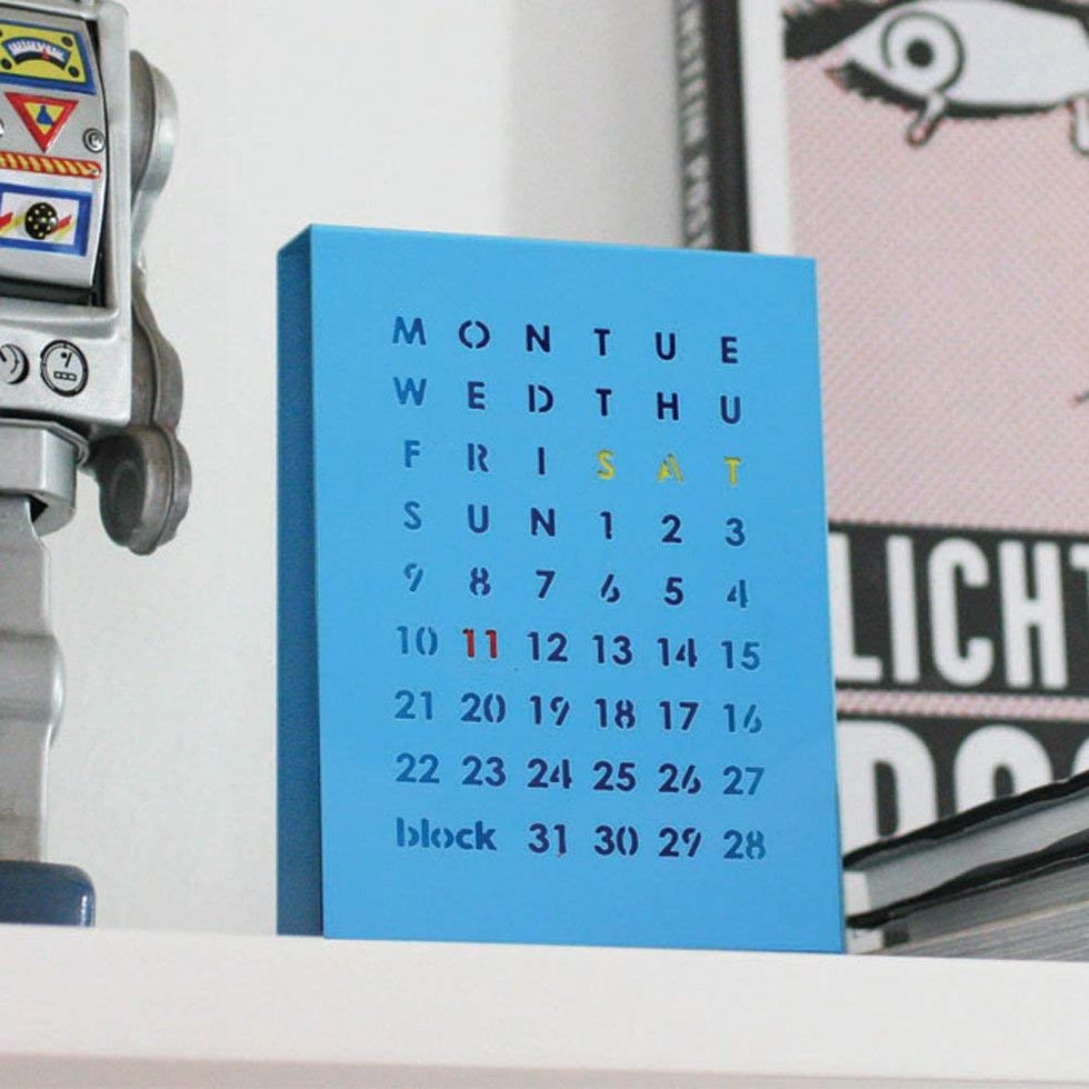 A blue perpetual calendar next to a toy robot.