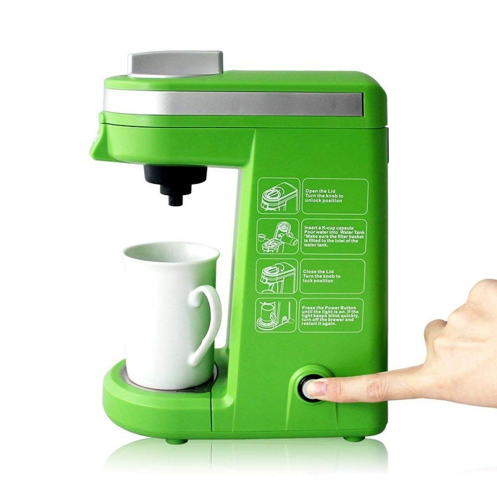 A person brewing a fresh cup of coffee with a green single-cup coffee brewer.