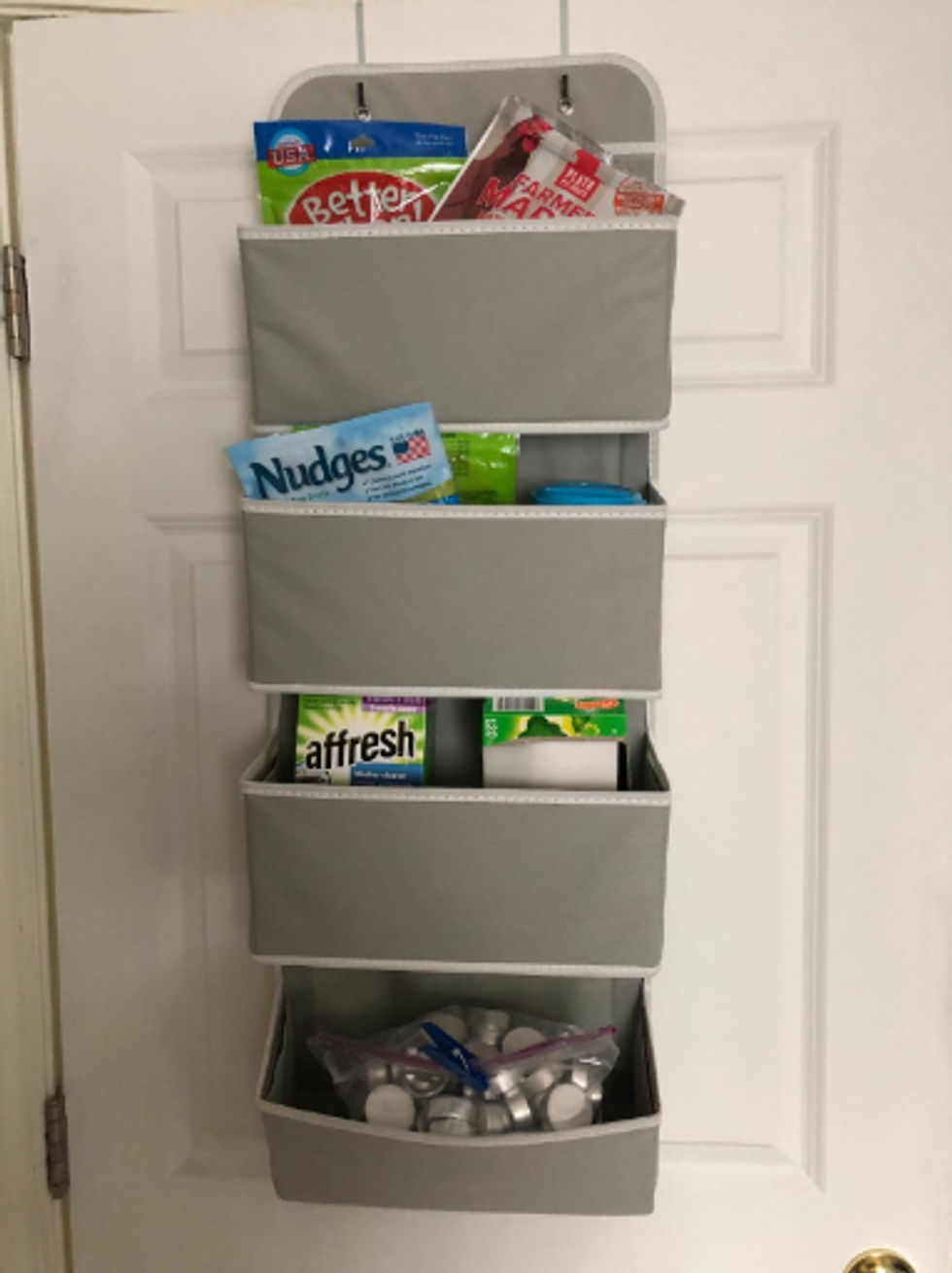 An over the door organizer full of snacks and other household items.