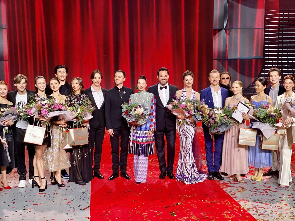 A staggered line of 17 men and women in dress clothes stand and smile for the camera in front of a red curtain. The first-created and first-viewed YouTube channel was 