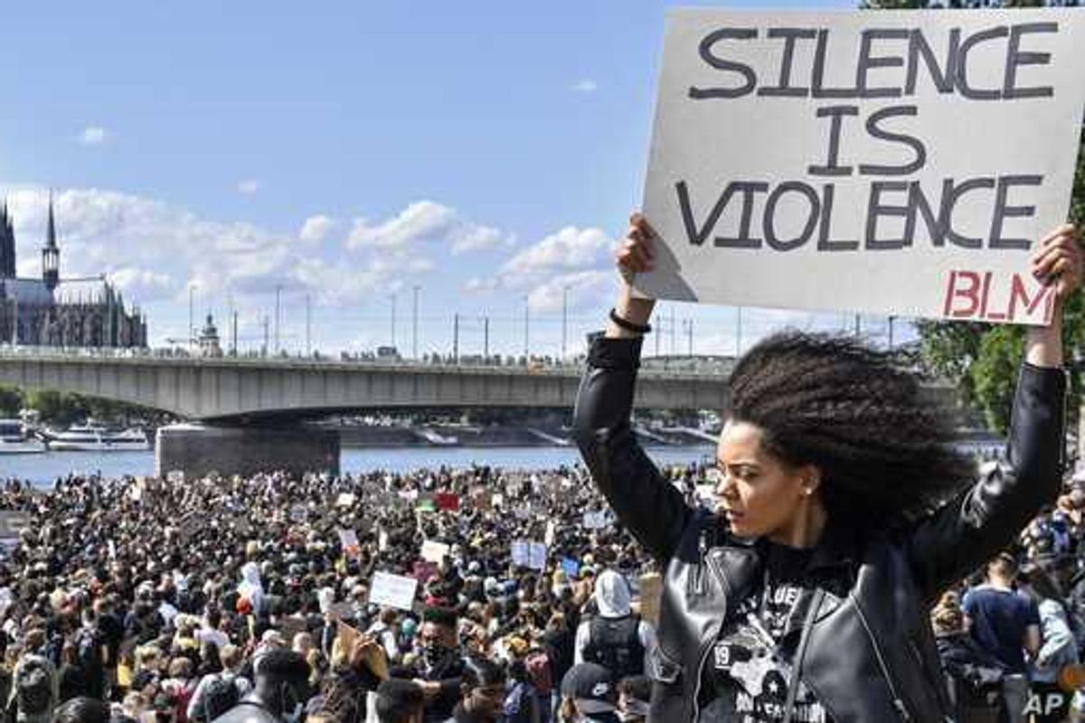 Black woman holding a sign that says "silence is violence"