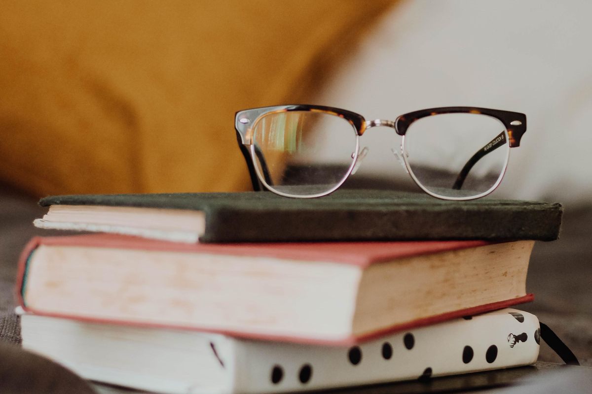 Stack of books with a pair of glasses on top. 