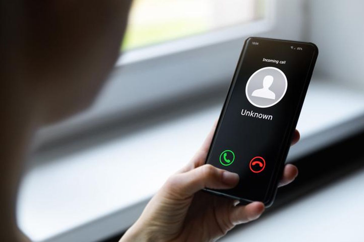 A hand holding a smartphone with an unknown caller coming through