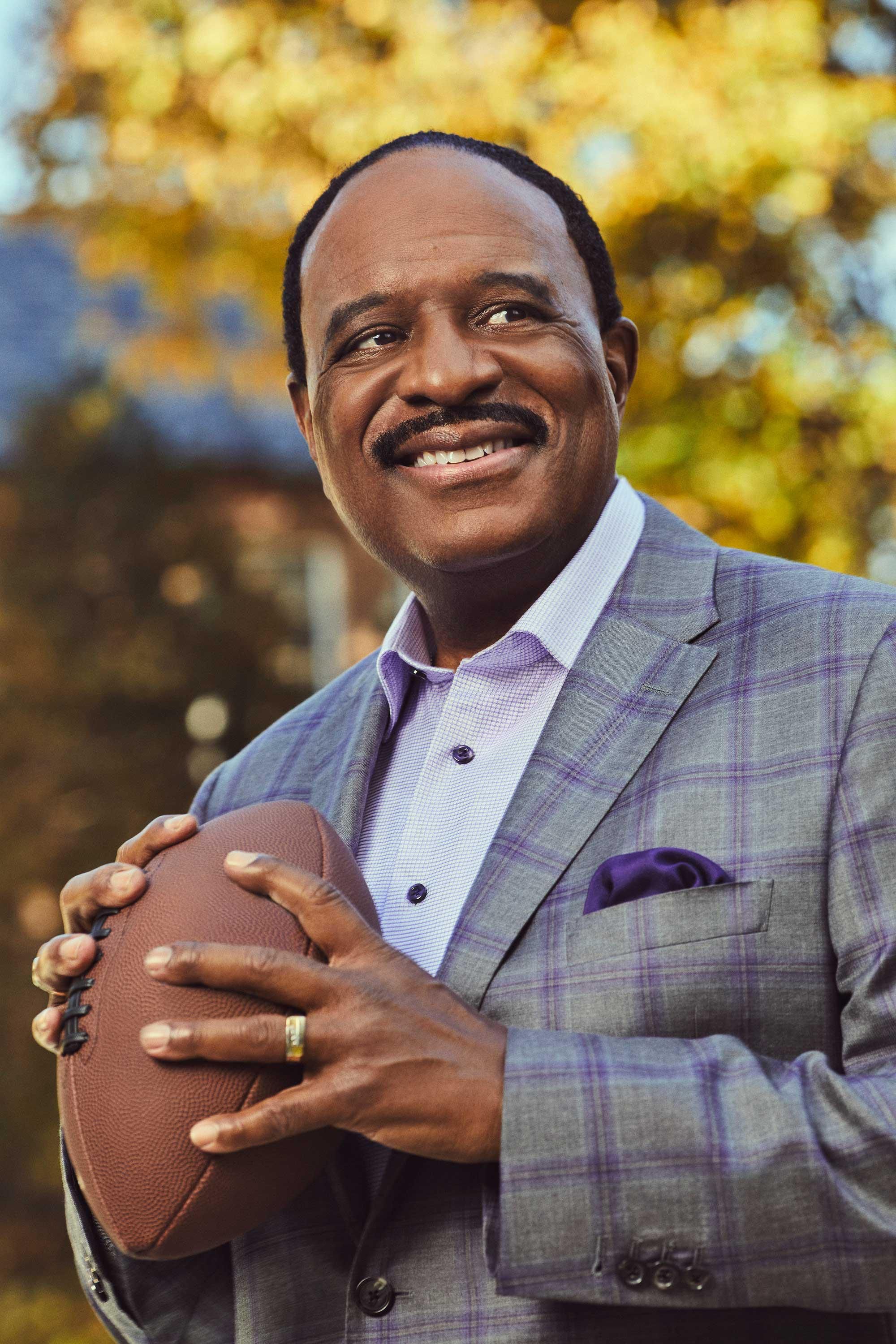 The NFL Today's host James Brown poses in a park with a football and a grin.