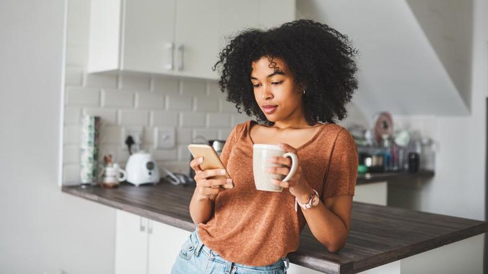 A woman holding a smartphone in a kitchen