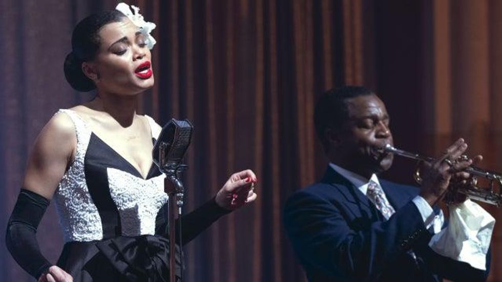 Still of Andra Day as Billie Holiday singing on stage (left) with a trumpet player (right)