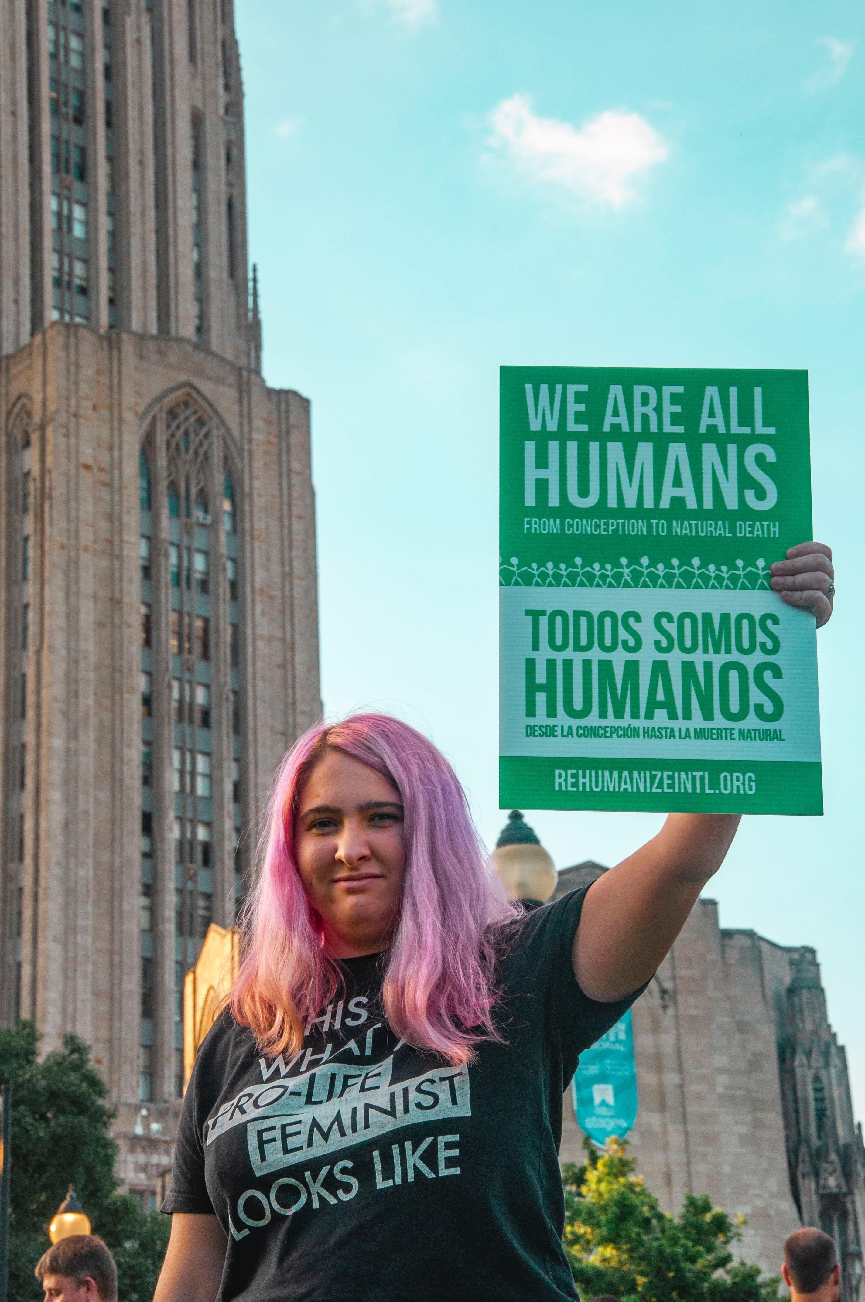 Woman holding 'We Are All Humans' sign 